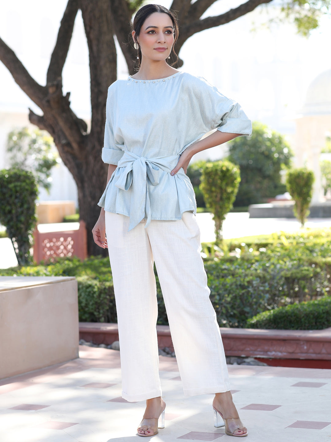 A Light Blue Color Self Weaved Embellished Top With Tie-Up At The Waist And Extended Sleeves Top With Cotton White Flared Pants